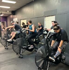 gym members on the assault bike during a group class